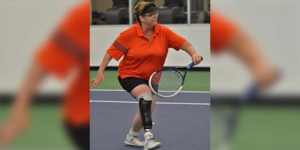 A para-standing player reaching for a backhand on an indoor court
