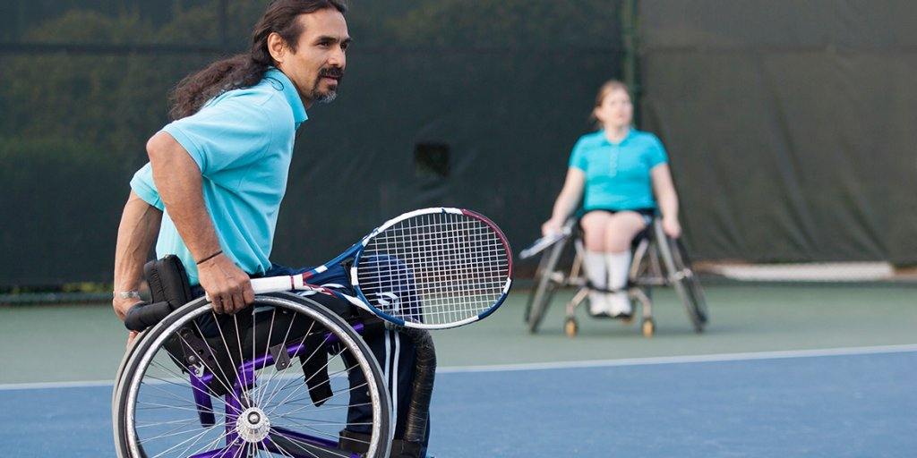 Two wheelchair players during a rally on an outdoor court
