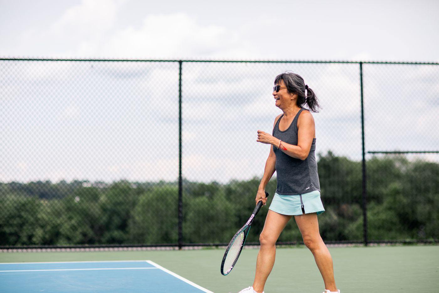 An adult player walking back to the baseline between points on a Houston public court