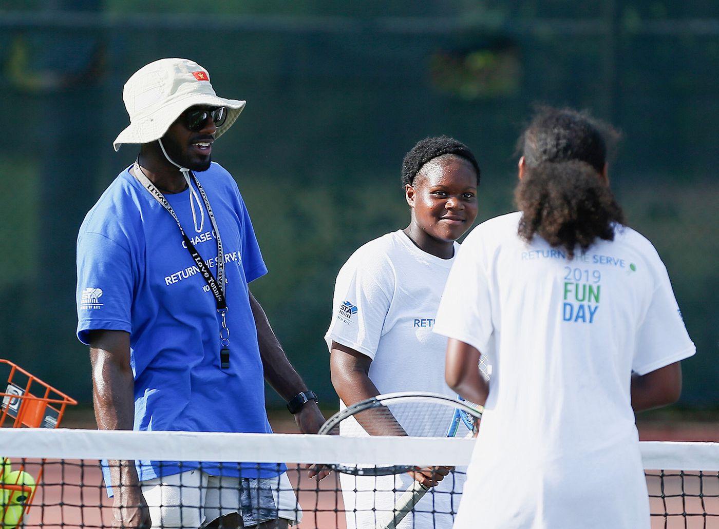 A coach working with a junior player at the net