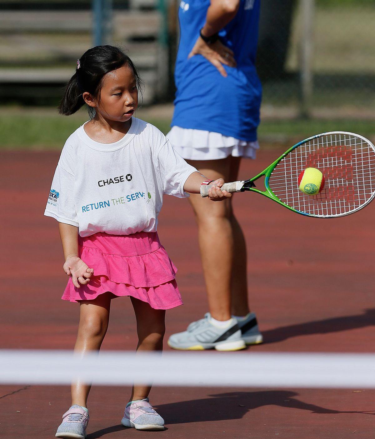 Una jugadora pequeña con raqueta y pelota roja