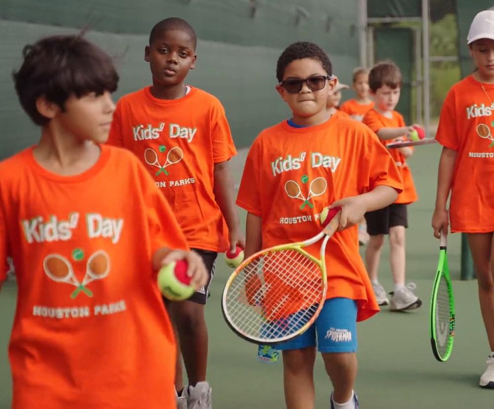Children in Kids&rsquo; Day shirts walking onto the courts carrying racquets and red balls