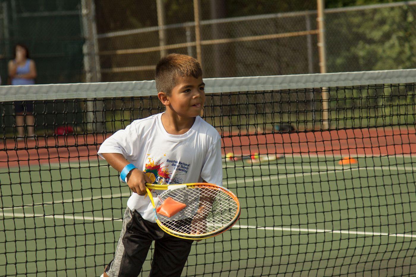 A young player striking a red ball forehand