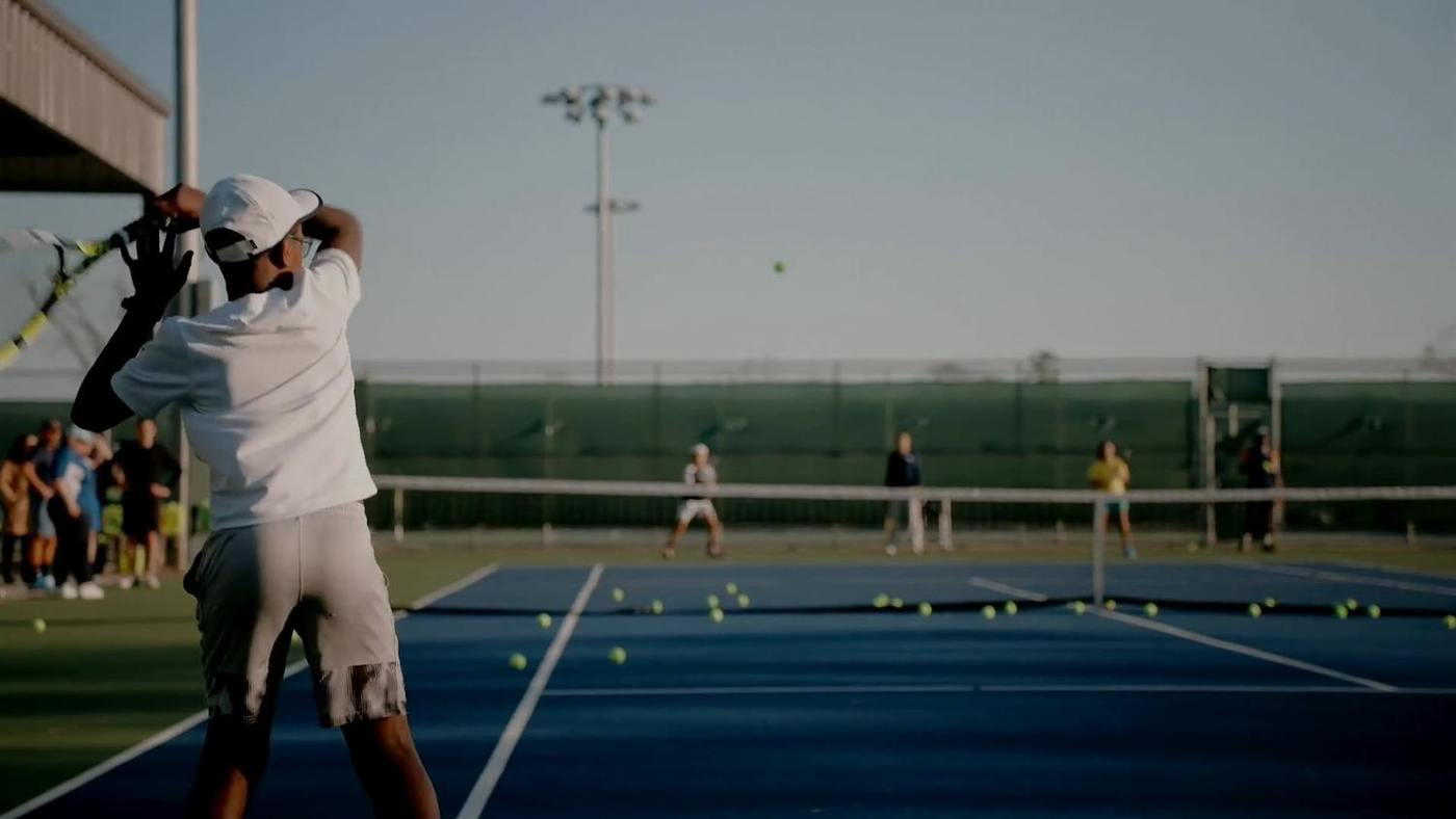 Adult players serving on a Houston court at dusk